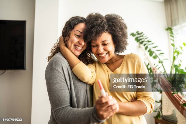 lesbian couple holding a pregnancy test at home - gynecological examination stock pictures, royalty-free photos & images