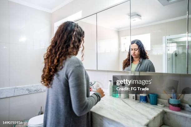 mulher nova olhando um teste de gravidez no banheiro em casa - teste de diagnóstico rápido - fotografias e filmes do acervo
