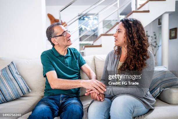 traurige junge frau, die von ihrem vater im wohnzimmer zu hause getröstet wird - alte und junge lesbische frauen stock-fotos und bilder