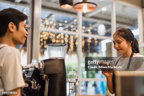 an asian man and woman working in a traditional cafe in bali. - pinafore dress stock pictures, royalty-free photos & images