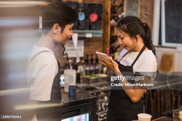 an asian man and woman working in a traditional cafe in bali. - pinafore dress stock pictures, royalty-free photos & images