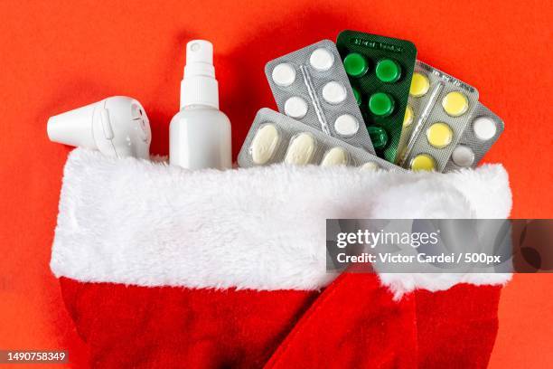 close-up of pills,thermometer and antiseptic in santa hat on red background,romania - coronavirus romania stock pictures, royalty-free photos & images
