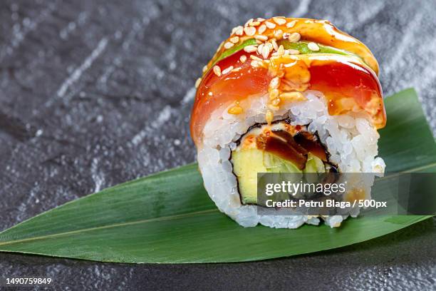 close - up of sushi rainbow dragon on a green leaf on a black background,romania - maki sushi stockfoto's en -beelden