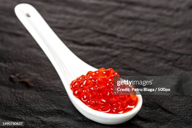 salted red caviar in a white spoon on a black stone background,romania - red caviar stock pictures, royalty-free photos & images