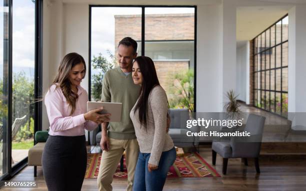 agente inmobiliario mostrando una casa en venta a una pareja - agente inmobiliario fotografías e imágenes de stock