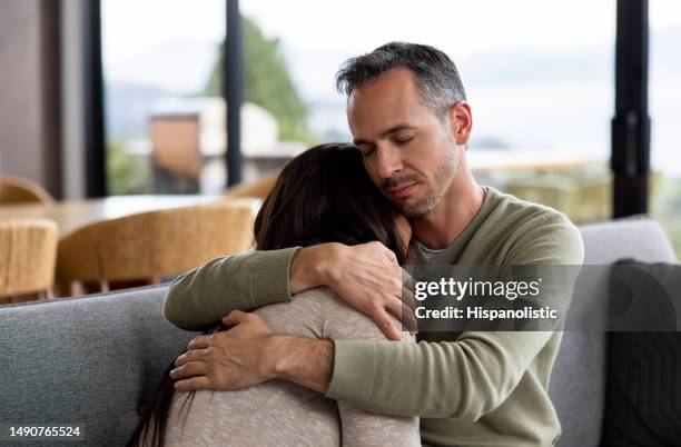 loving man comforting his wife grieving - couple unhappy stockfoto's en -beelden