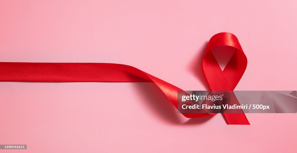 Red ribbon symbol of world aids day on pink background banner format,Romania