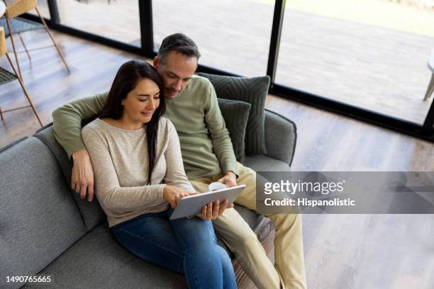 couple relaxing at home making an online reservation using a tablet computer - coffe house live stock pictures, royalty-free photos & images