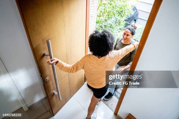 lesbian couple embracing on the entrance hall at home - house warming stock pictures, royalty-free photos & images