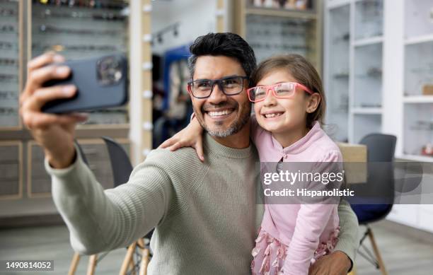 père et fille prenant un selfie en essayant des lunettes dans un magasin d’optométrie - lunettes de vue photos et images de collection