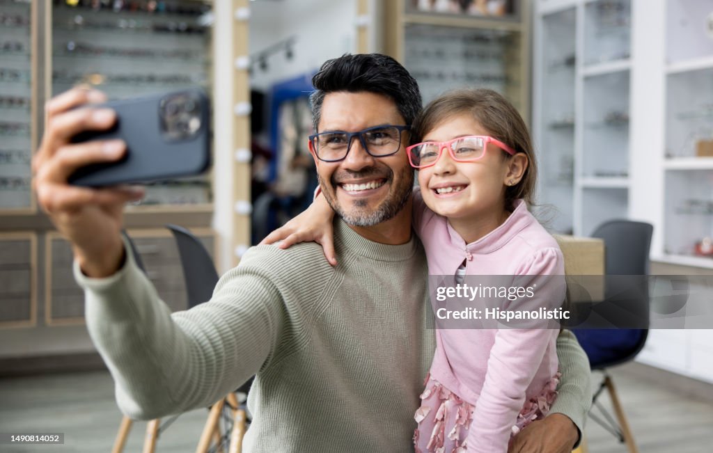 Father and daughter taking a selfie trying glasses at an optometry shop