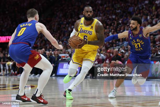 LeBron James of the Los Angeles Lakers drives to the basket between Christian Braun and Jamal Murray of the Denver Nuggets during the first quarter...