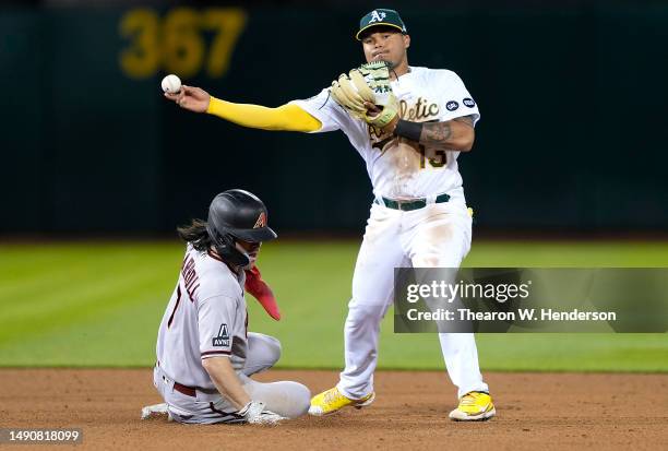 Jordan Diaz of the Oakland Athletics completes the double-play throwing to first base over the top of Corbin Carroll of the Arizona Diamondbacks in...