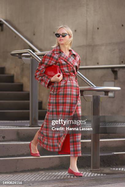 Violet Grace Atkinson wearing red check coat, Mimco red clutch at Afterpay Australian Fashion Week 2023 at Carriageworks on May 17, 2023 in Sydney,...