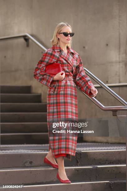 Violet Grace Atkinson wearing red check coat, Mimco red clutch at Afterpay Australian Fashion Week 2023 at Carriageworks on May 17, 2023 in Sydney,...