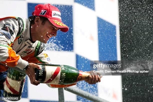 Italian Force India Formula One team racing driver Giancarlo Fisichella on the winners podium wearing his logo adorned fire protection suit overalls...