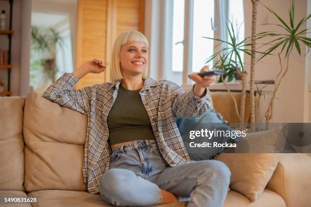 woman enjoying her favorite tv show at home - tv show stockfoto's en -beelden