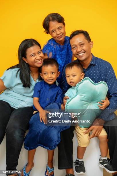 studio portrait of family mother father boys grandmother in front of bright yellow background - indonesia photos 個照片及圖片檔