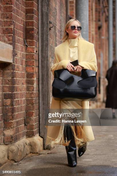 Violet Grace Atkinson wearing yellow Camilla and Marc coat, Ferragamo oversized black clutch and Givenchy black boots at Afterpay Australian Fashion...