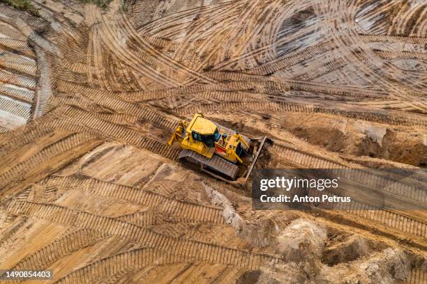 bulldozer is leveling the ground at the construction site. aerial view - movimiento de tierras fotografías e imágenes de stock