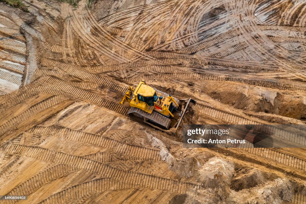 Bulldozer is leveling the ground at the construction site. Aerial view