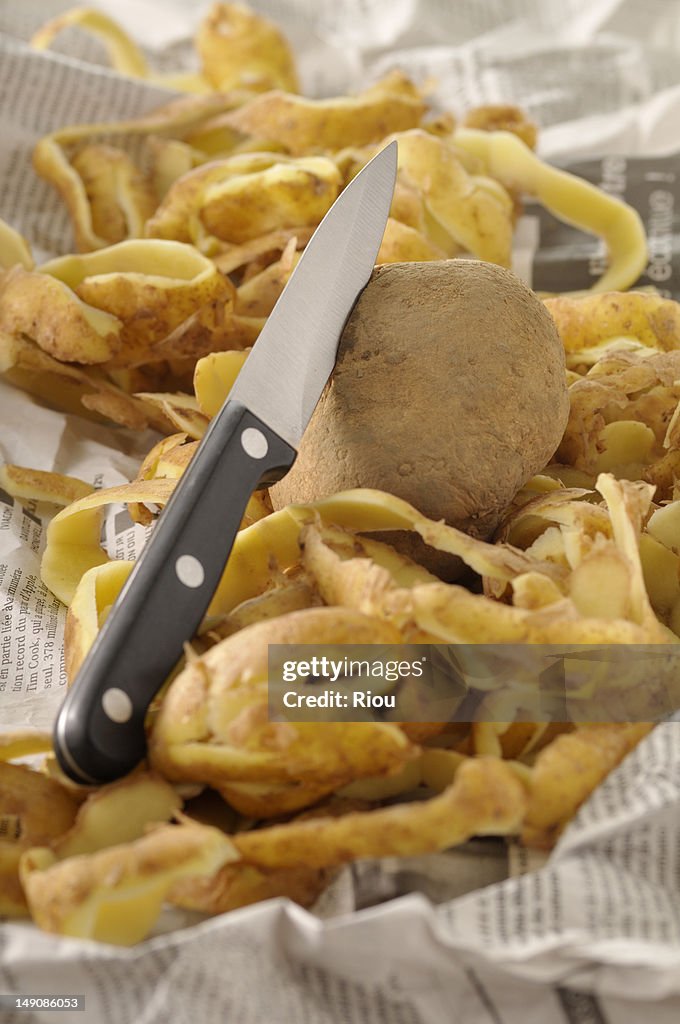 A potato, knife and peelings