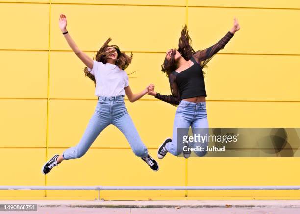 young arab and black women jump quickly in front of a yellow wall - islamic action front stock pictures, royalty-free photos & images