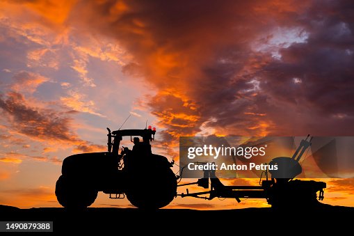 Tractor plowing a field at sunset. Preparing the field for sowing