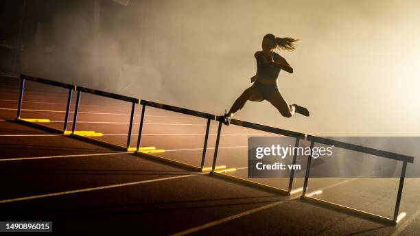 woman silhouette jumping through hurdle - sprint track stock pictures, royalty-free photos & images