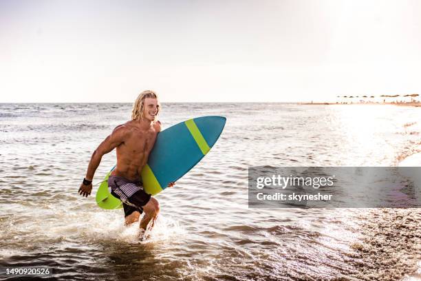 happy surfer running out of the sea in summer day. - ulcinj stock pictures, royalty-free photos & images