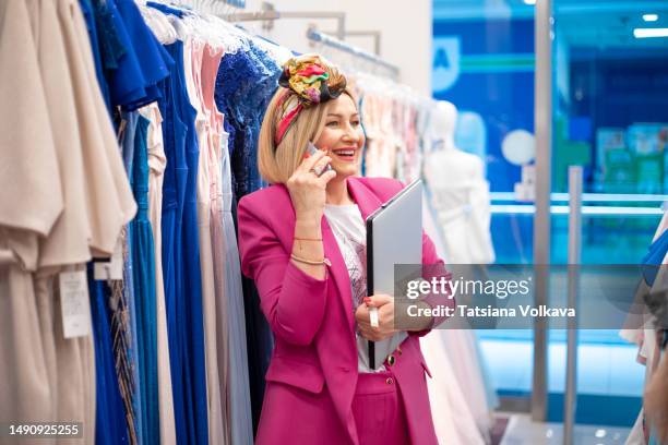 elegant female designer in pink jacket and headband talking about her new fashion collection on phone - budding starlets stock-fotos und bilder