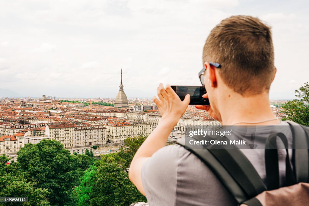 Tourist photographing historical center of Turin with smart phone