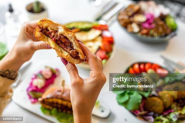 woman eating vegan burger - vegan bildbanksfoton och bilder