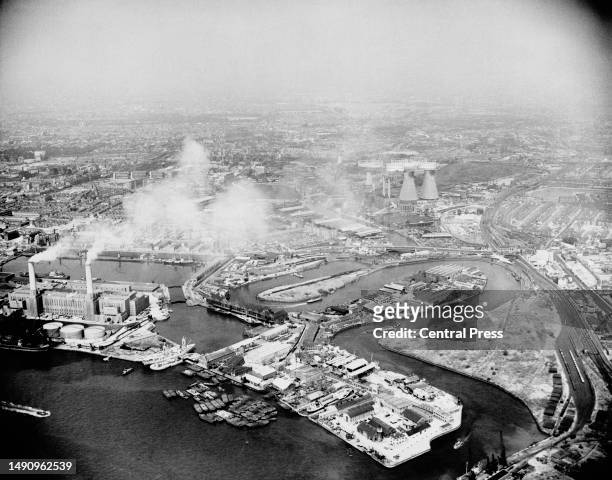 Smoke from the Brunswick Wharf Power Station partially obscures this aerial view of the Port of London, showing East India Dock and Bow Creek, on the...