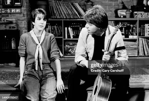 View of MTV VJ Martha Quinn and American Blues & Rock musician George Thorogood, both sitting on a low stage, during an interview on MTV at...