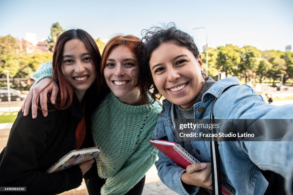 Porträt von jungen Freundinnen/Studentinnen, die ein Selfie auf der Straße machen - Kameraperspektive