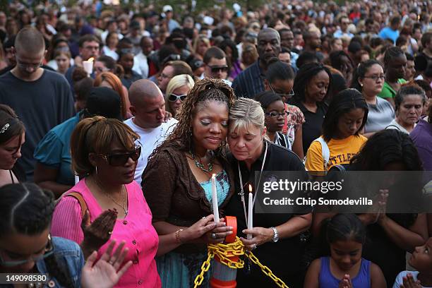 Titia Stillwell and Lori Meade embrace and pray with thousands of others during a prayer vigil for the victims of Friday's movie theater mass...