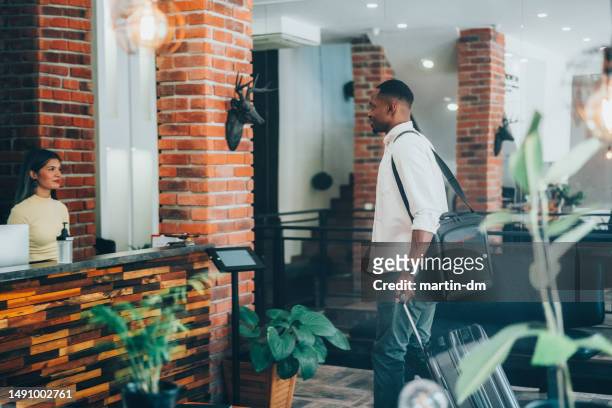 businessman just arriving in hotel is filling out registration form at the reception - hotel reopening stock pictures, royalty-free photos & images