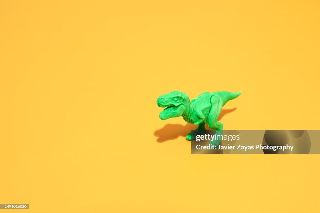 Green Plastic Tyrannosaurus Rex On Yellow Background