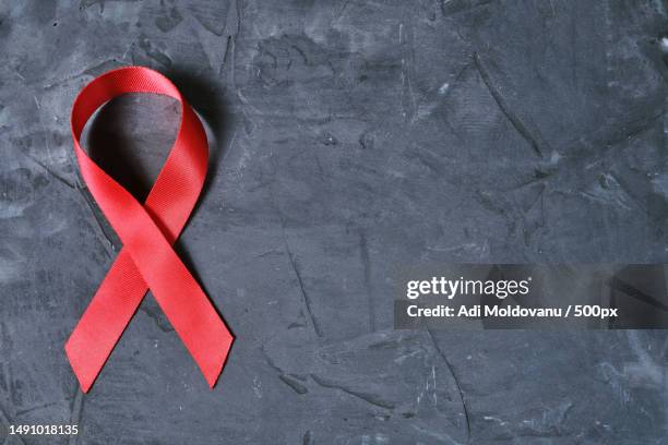 red ribbon on concrete texture background,symbol of aids disease and drug abuse problem,romania - aids imagens e fotografias de stock