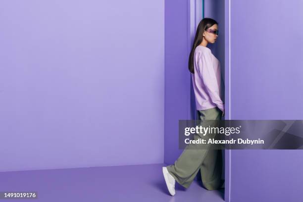 a fashionable beautiful woman comes out of a colored purple room at the door. fashion concept - entrar imagens e fotografias de stock