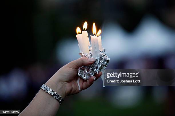Woman holds candles during a memorial service outside the Aurora Municipal Center July 22, 2012 in Aurora, Colorado. The memorial was for the victims...