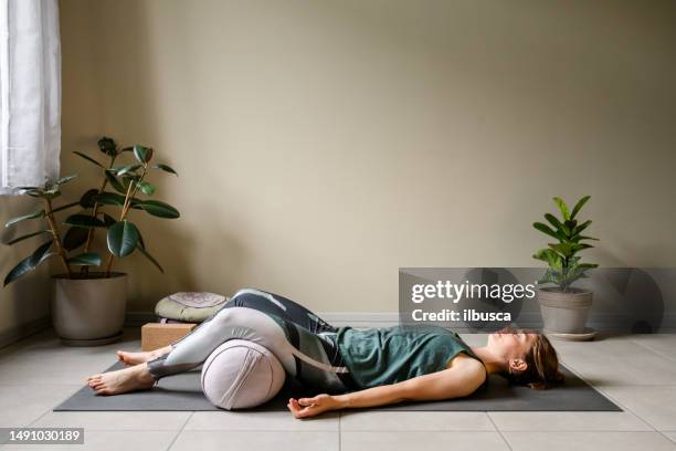 professional woman practicing yoga at home: corpse, shavasana - shavasana imagens e fotografias de stock