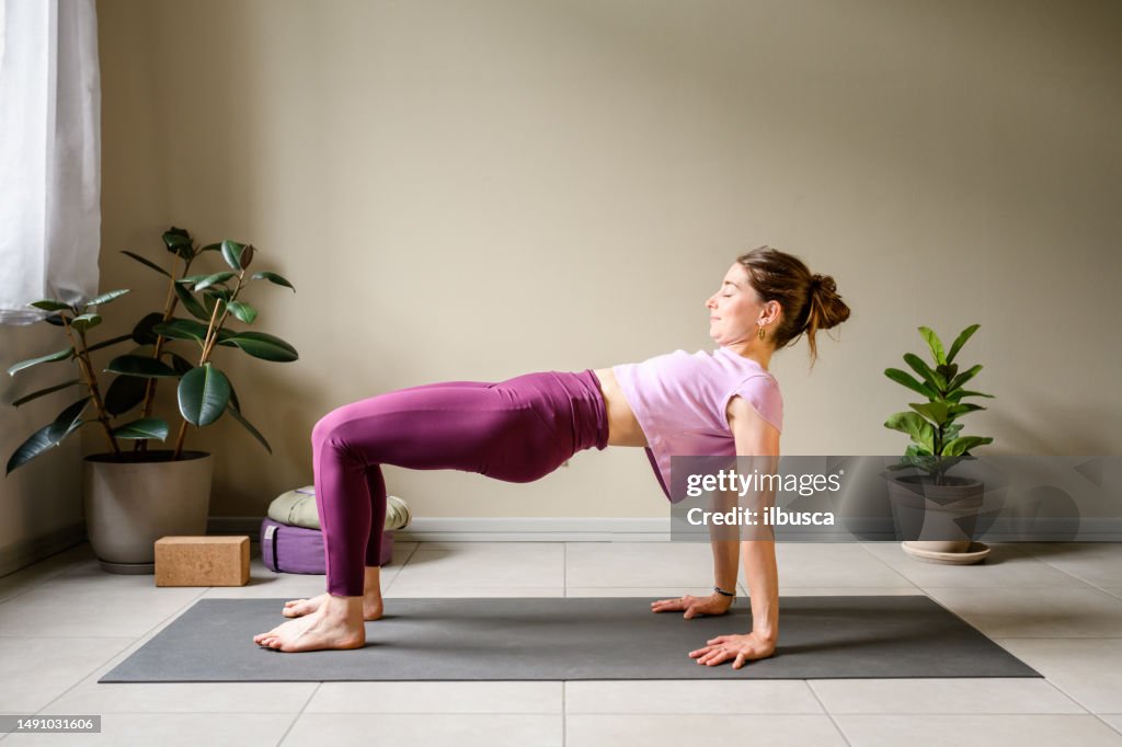 Professional woman practicing yoga at home: Upward Plank, Purvottanasana