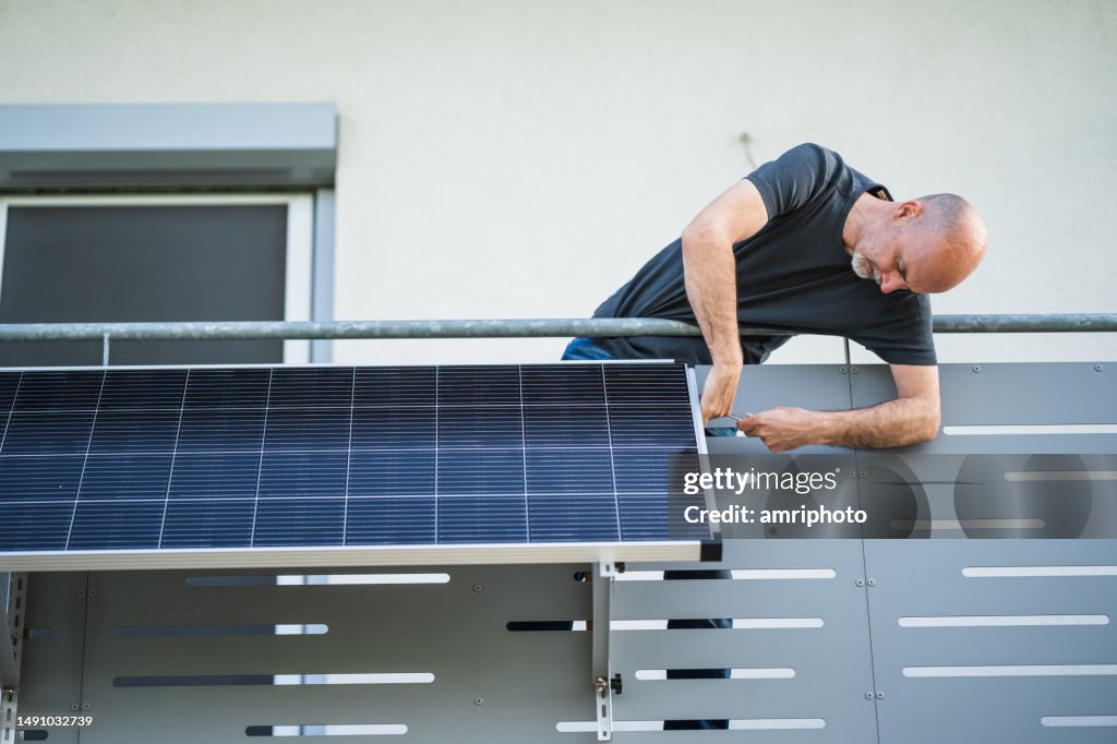 Man mounting solar panel on balcony