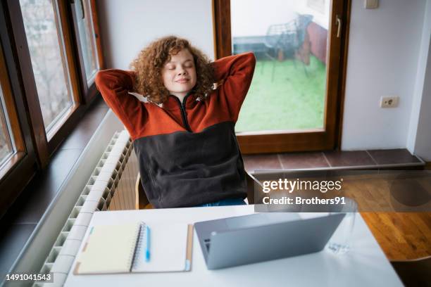 young woman taking a break from working on laptop at home - financial freedom stock pictures, royalty-free photos & images