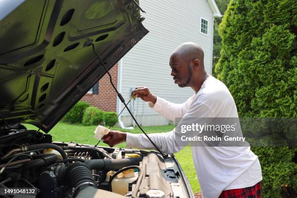 a portrait of a black man checking the oil level of a vehicle - engine failure stock pictures, royalty-free photos & images