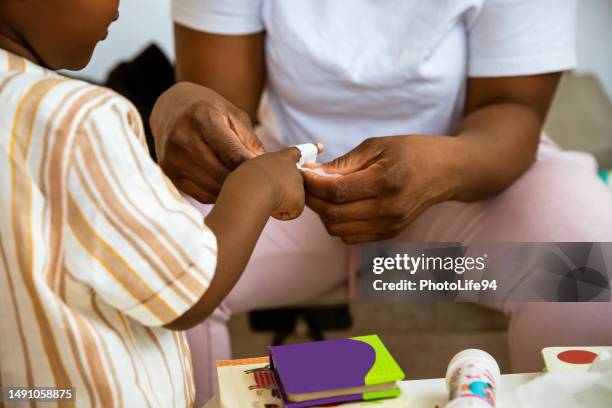 mama verbindet den finger eines verletzten kindes - schnittwunde stock-fotos und bilder