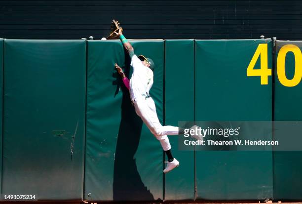 Esteury Ruiz of the Oakland Athletics leaps at the center field wall and watches the ball go over for a two-run home run hit by Corbin Carroll of the...