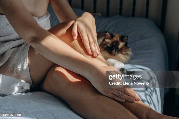 skin and body care, woman applies a moisturizing lotion to her legs and thighs after showering or a protective product after tanning, shadow overlay - esfoliazione foto e immagini stock